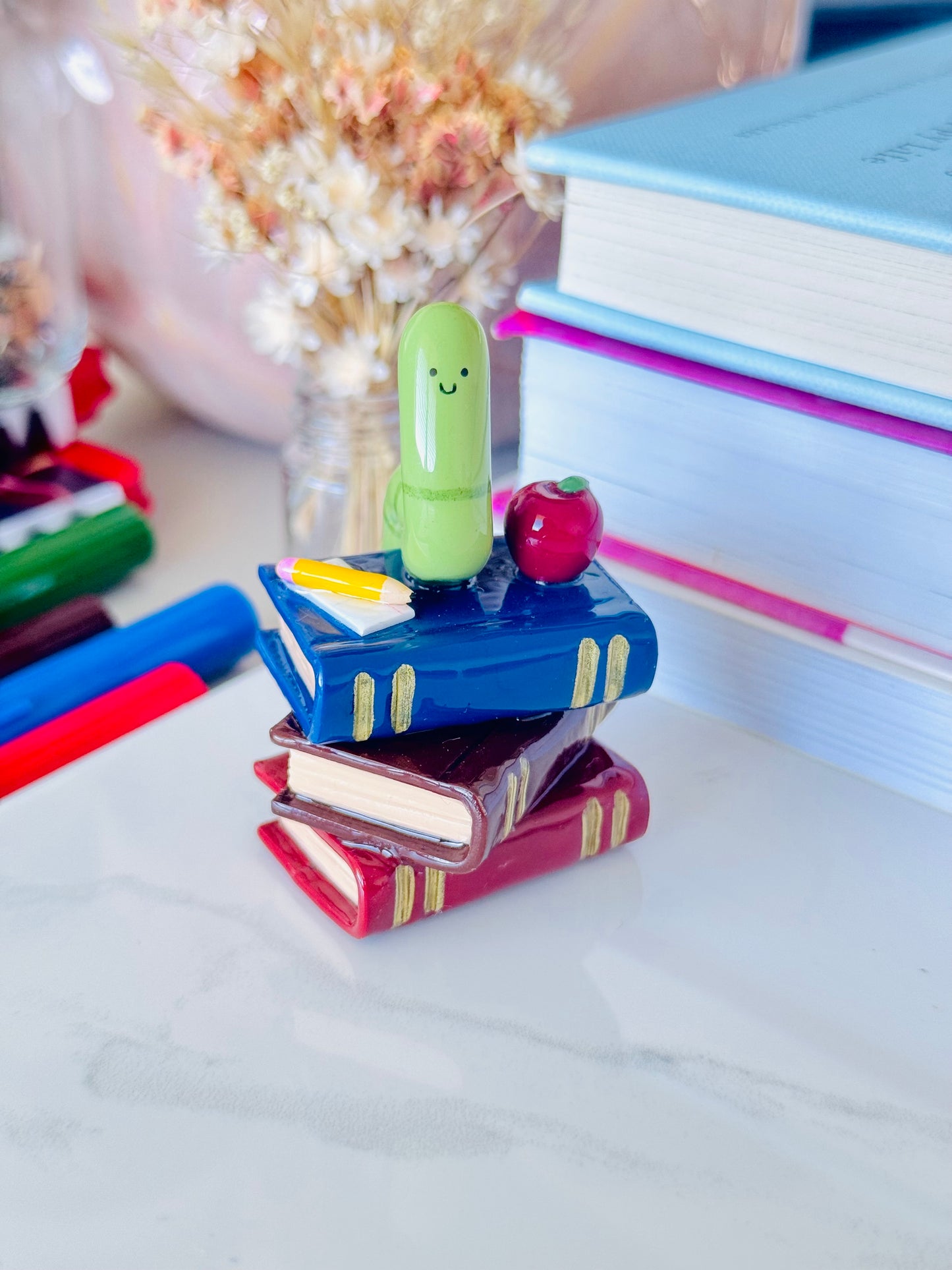 Wrigley the Worm desk friend handmade polymer clay figurine with books, apple, pen, and paper for desk décor