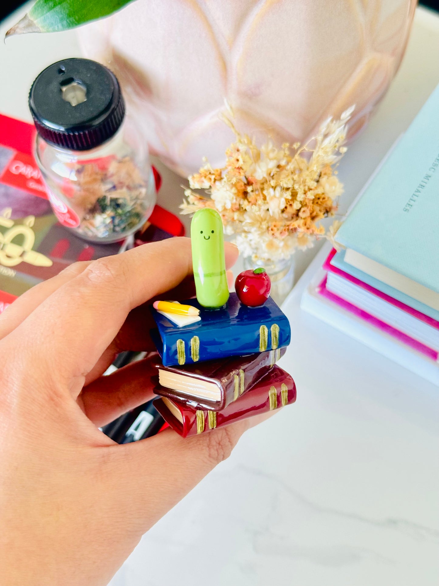 Wrigley the Worm desk friend handmade polymer clay figurine with books, apple, pen, and paper for desk décor