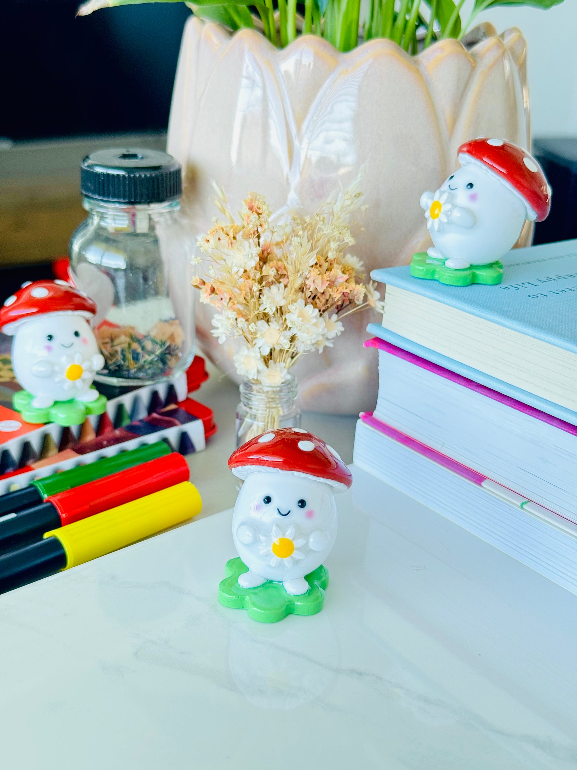 Desk with small decorative figures, books, and a vase with flowers.