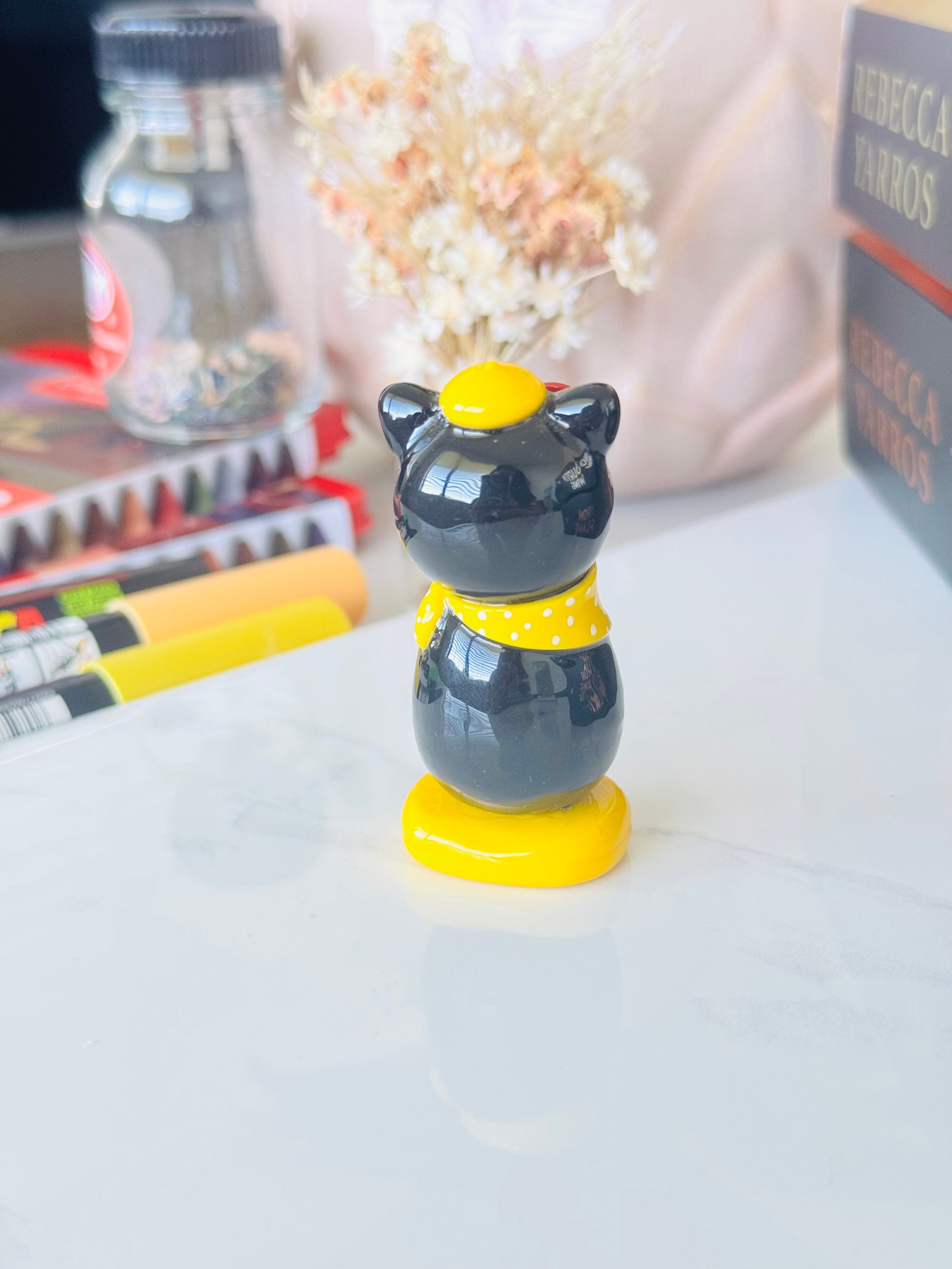 Black cat-shaped object with yellow accents on a white surface