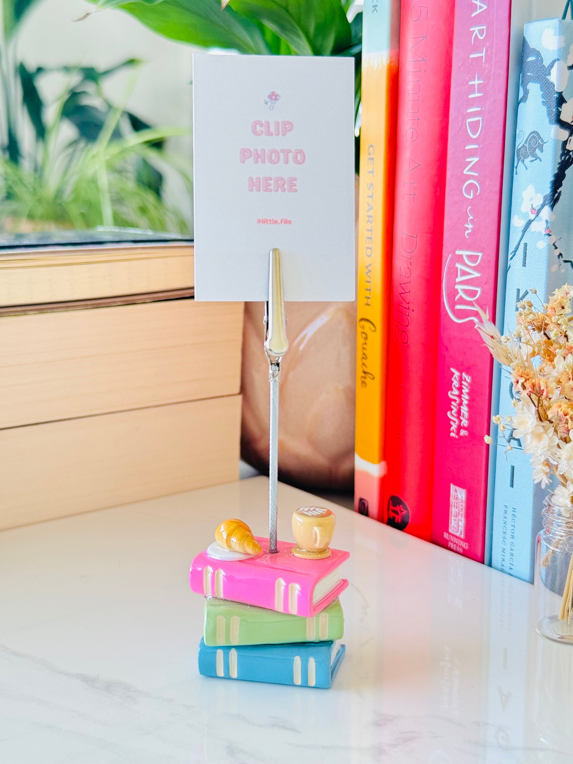 Colorful book stack with a photo clip holder on a surface