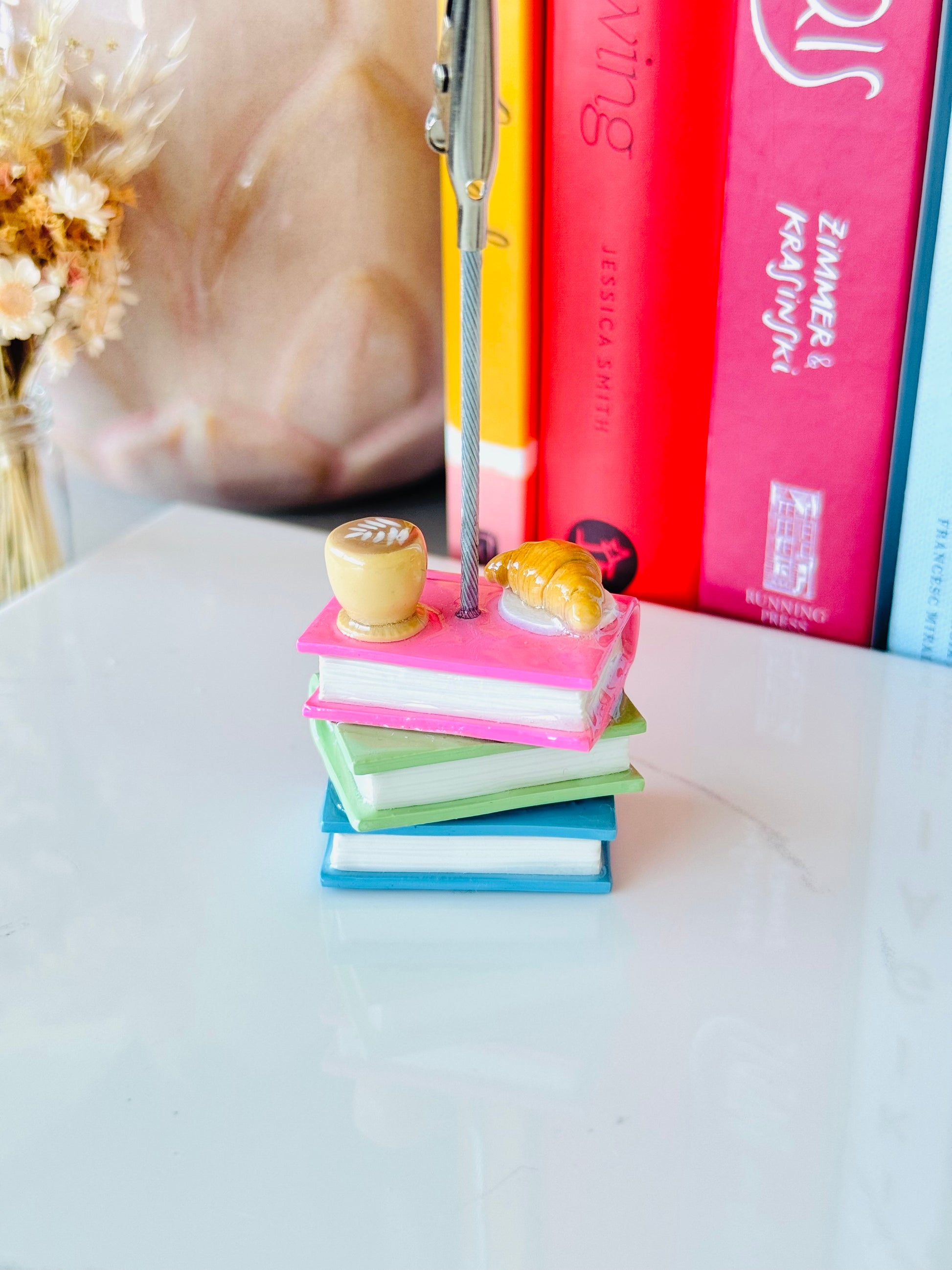 Stack of colorful books with decorative items on a light surface