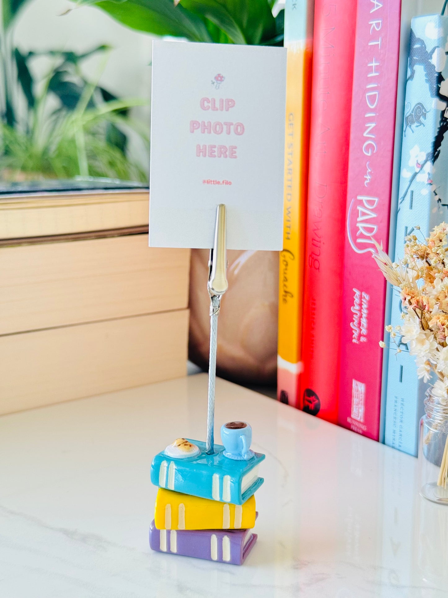 Colorful book-shaped photo clip holder with books in the background