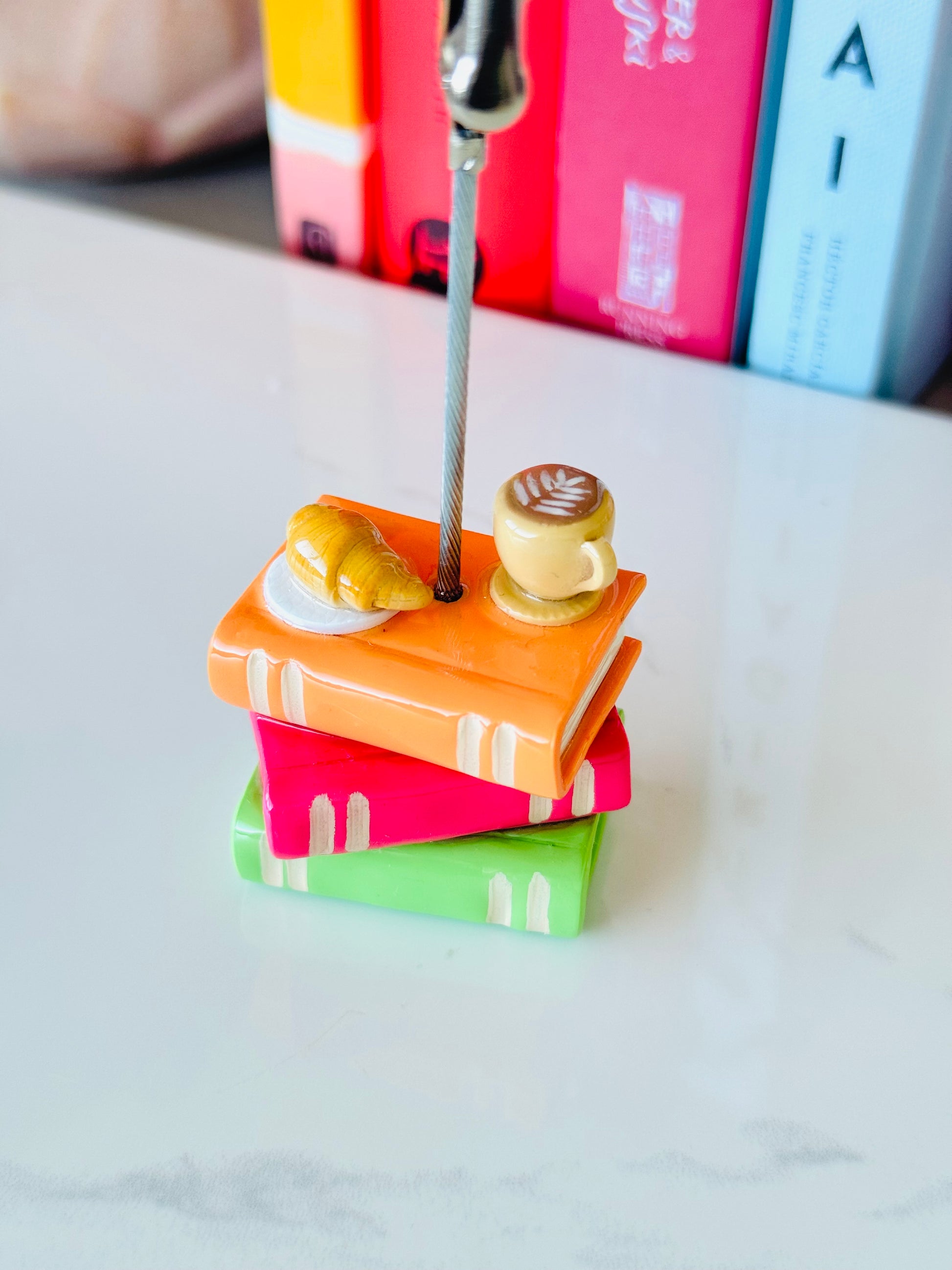 Colorful miniature books with a toy spoon and cake on a marble surface