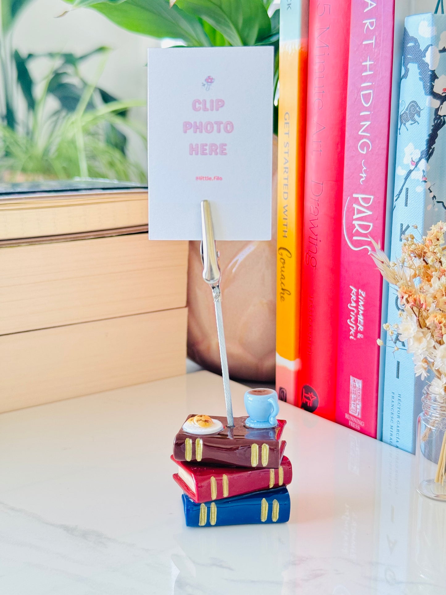Stack of colorful books with a photo holder on a surface, books in the background