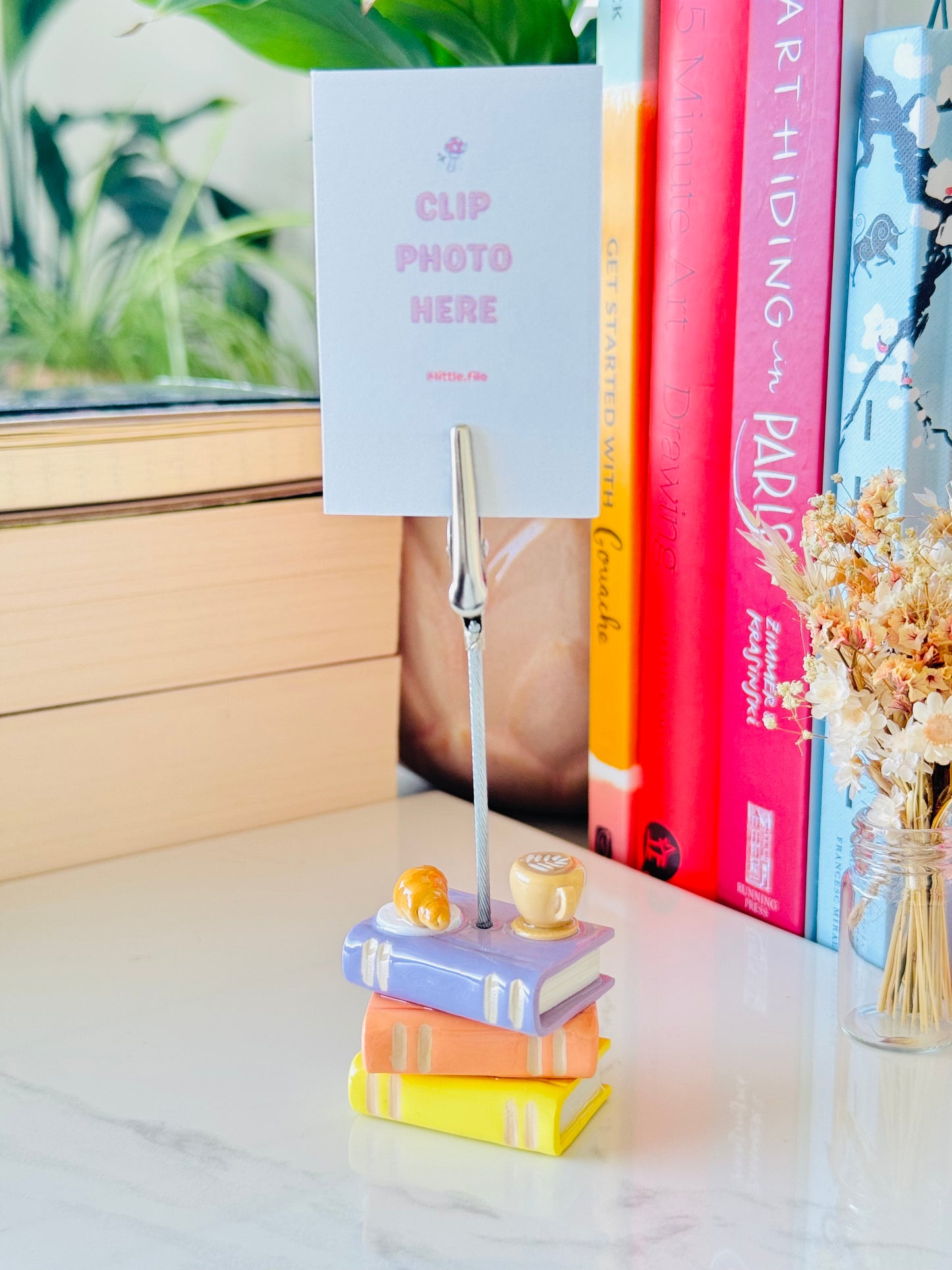 Colorful books stacked with a photo holder on a desk
