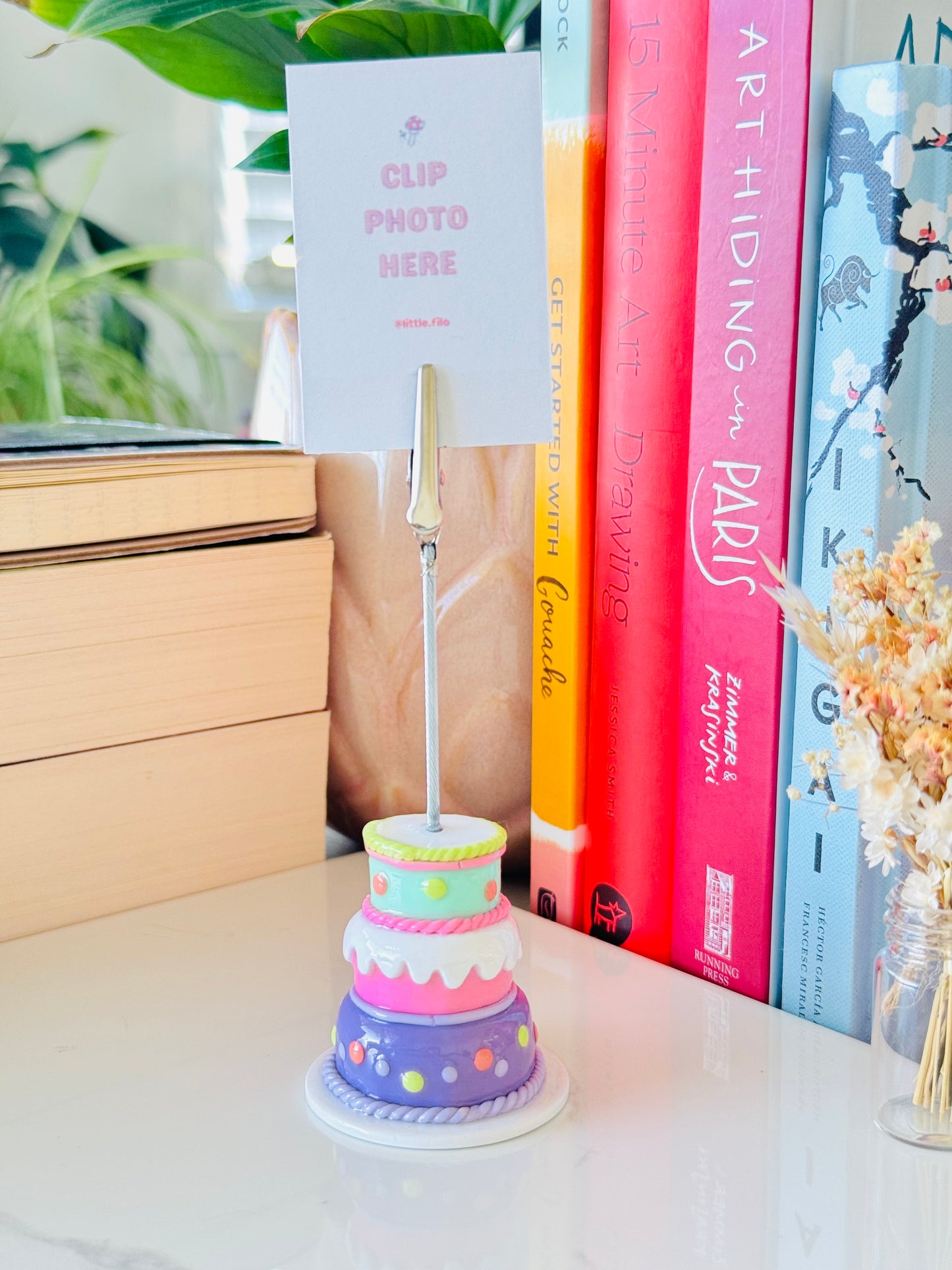 Colorful cake-shaped photo holder with a card on a desk with books in the background