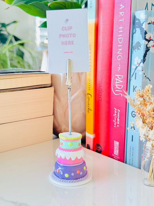Colorful cake-shaped photo holder with a card on a desk with books in the background