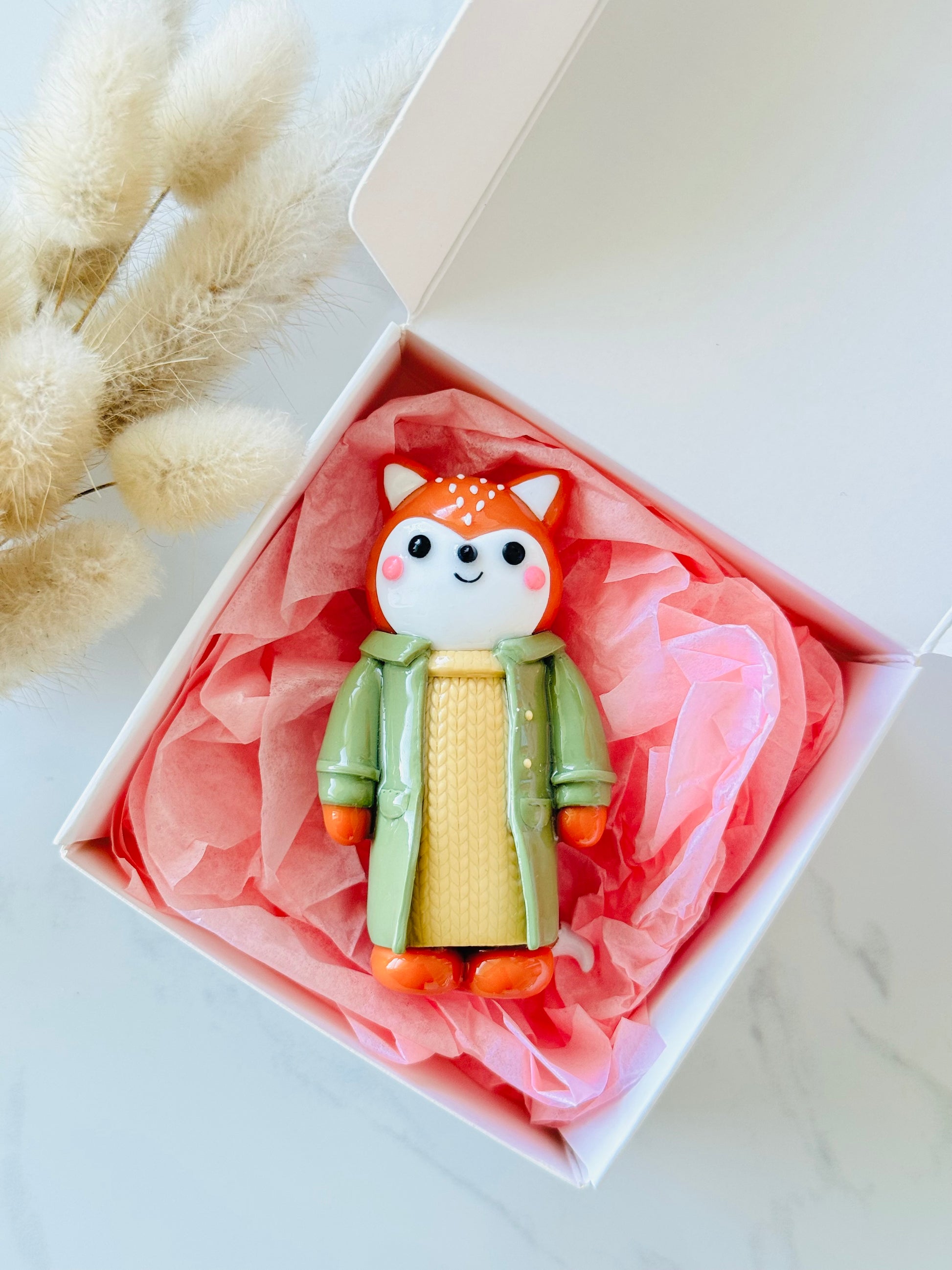 Toy fox figure in a decorative box with pink tissue paper on a light background