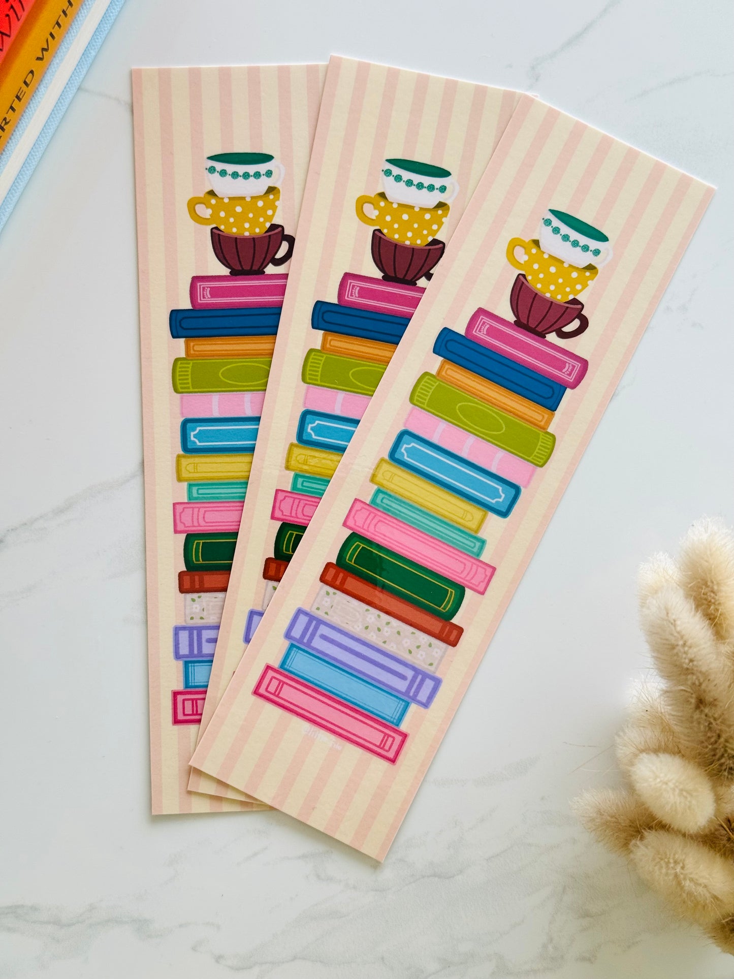Hand-illustrated bookmark with stacks of books and coffee cups
