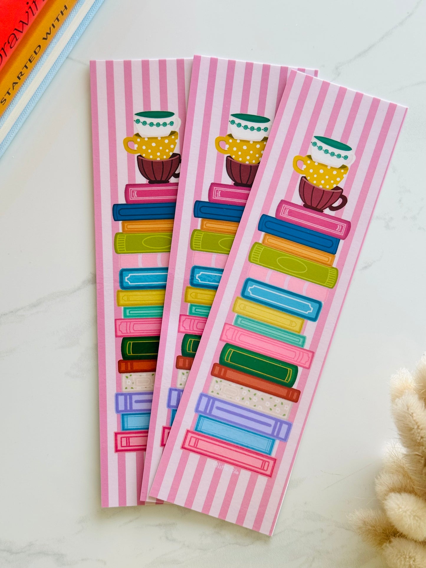 Hand-illustrated bookmark with stacks of books and coffee cups