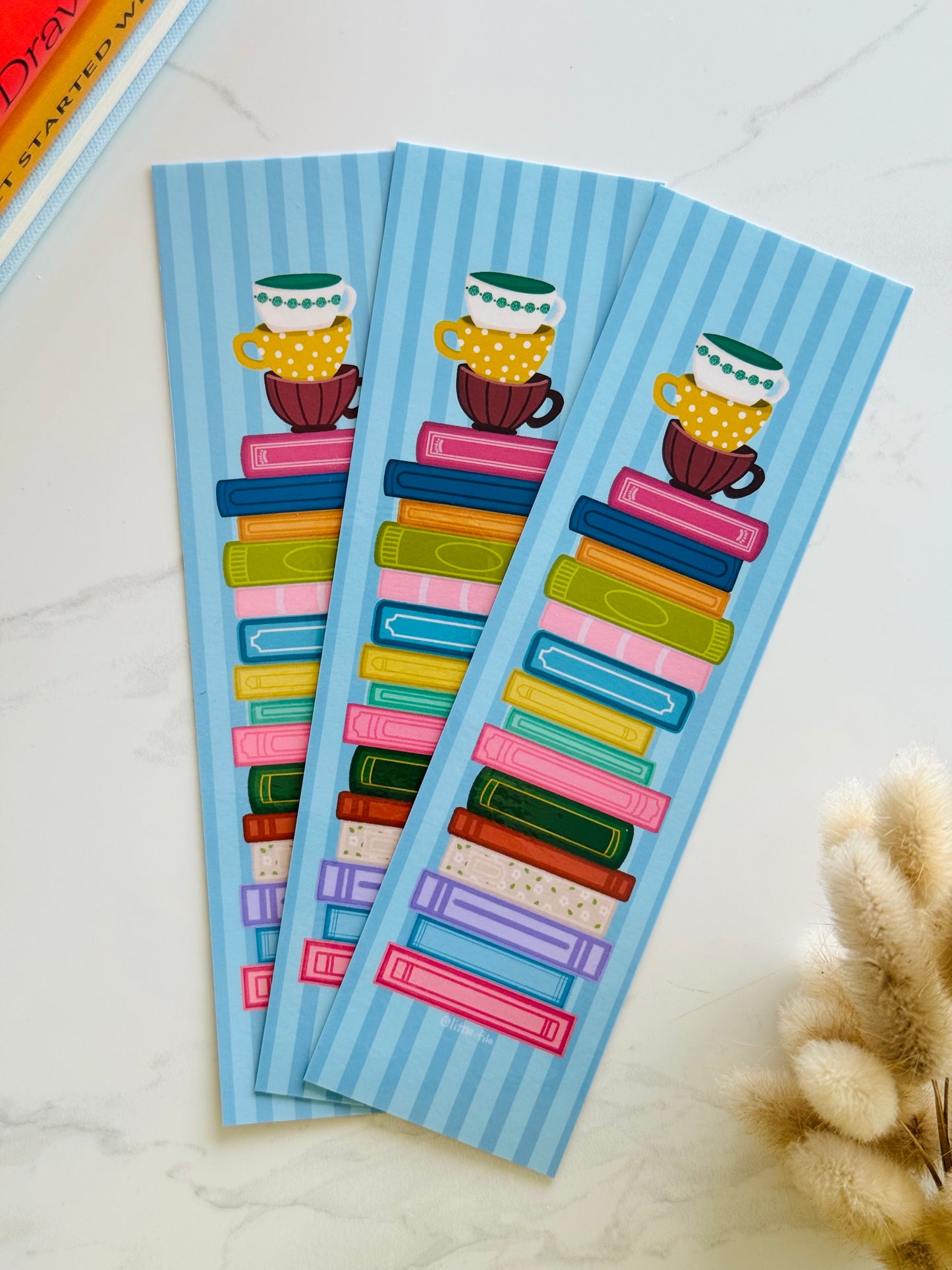 Hand-illustrated bookmark with stacks of books and coffee cups