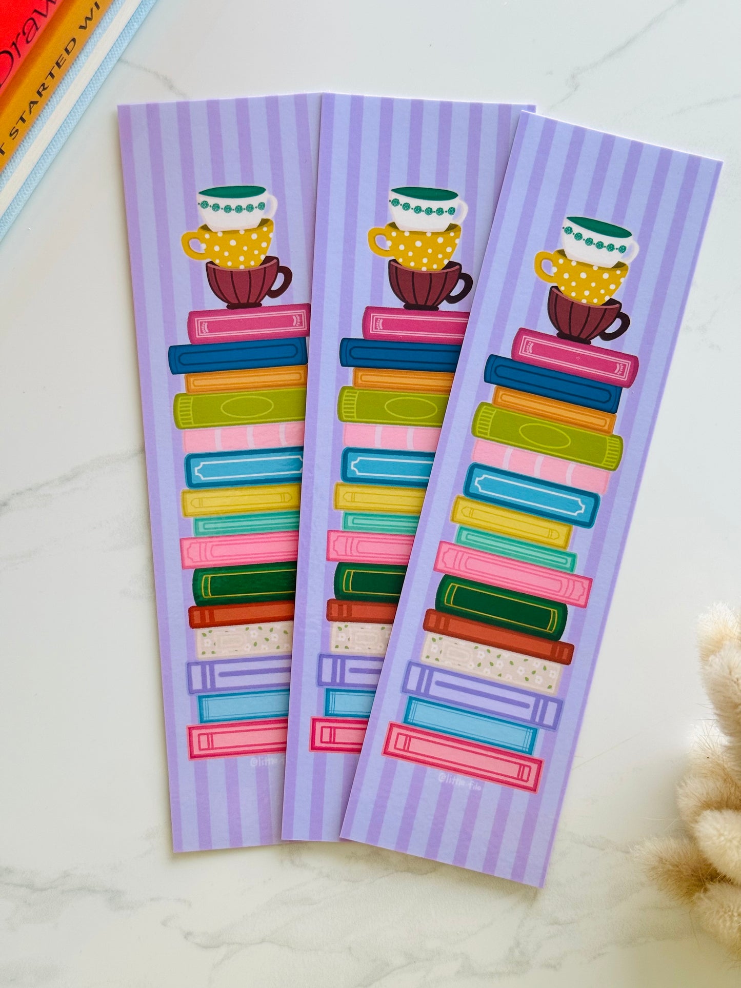 Hand-illustrated bookmark with stacks of books and coffee cups
