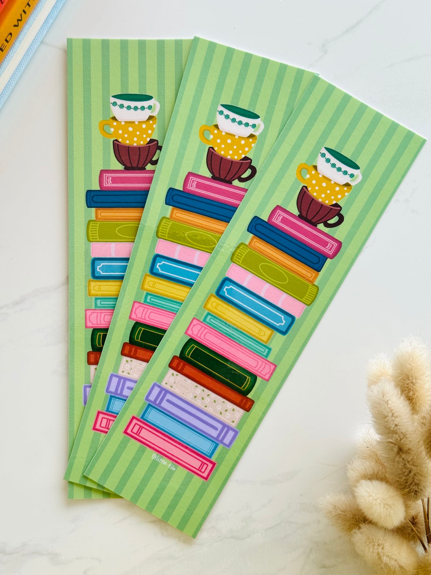 Hand-illustrated bookmark with stacks of books and coffee cups