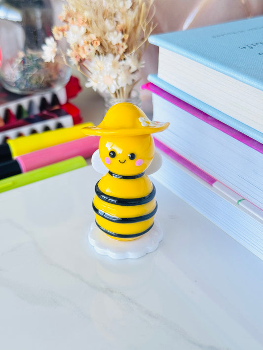 Yellow bee-shaped figurine on a desk with books and stationery items in the background