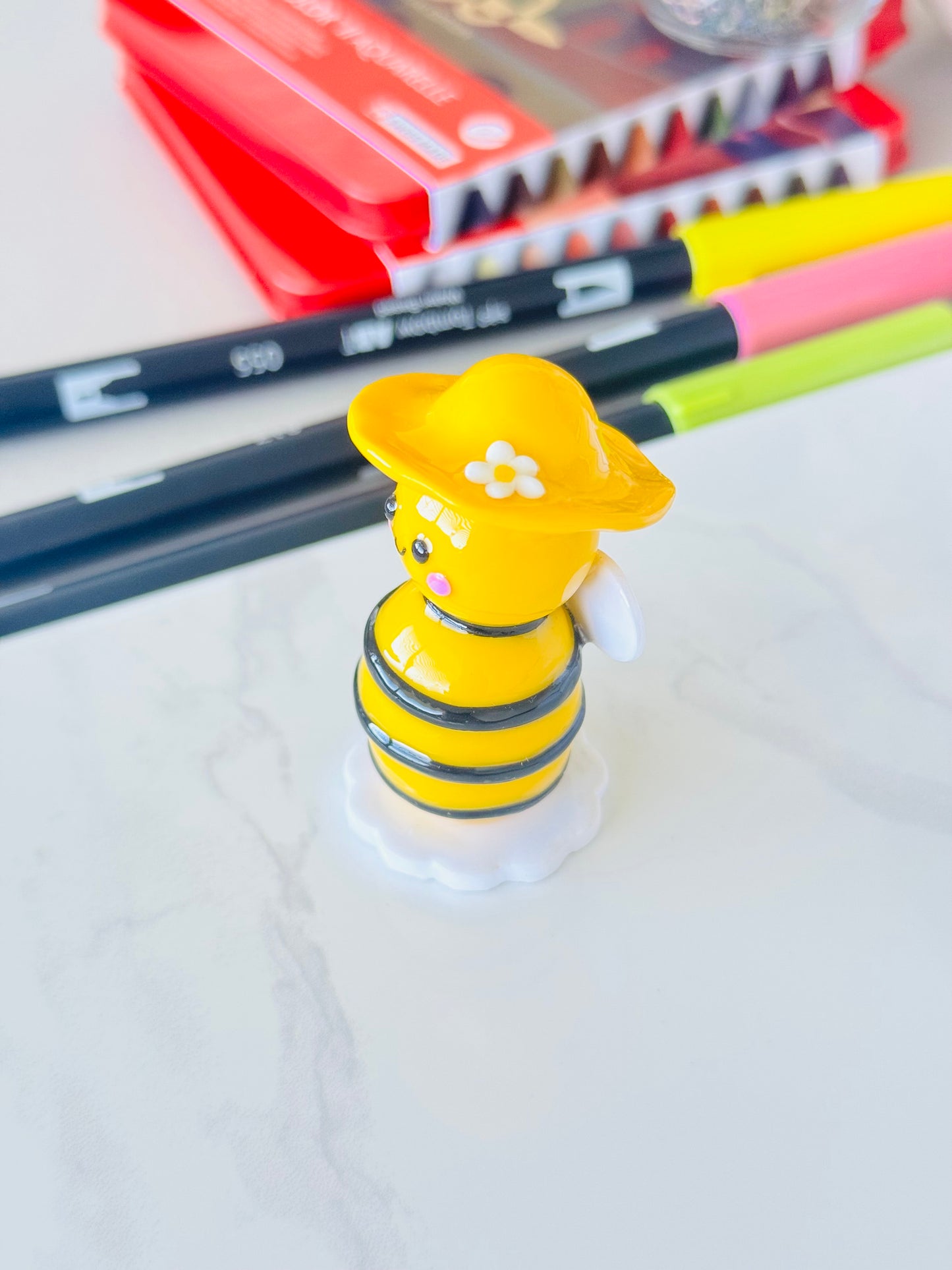 Yellow bee-shaped desk organizer with stationery items in the background