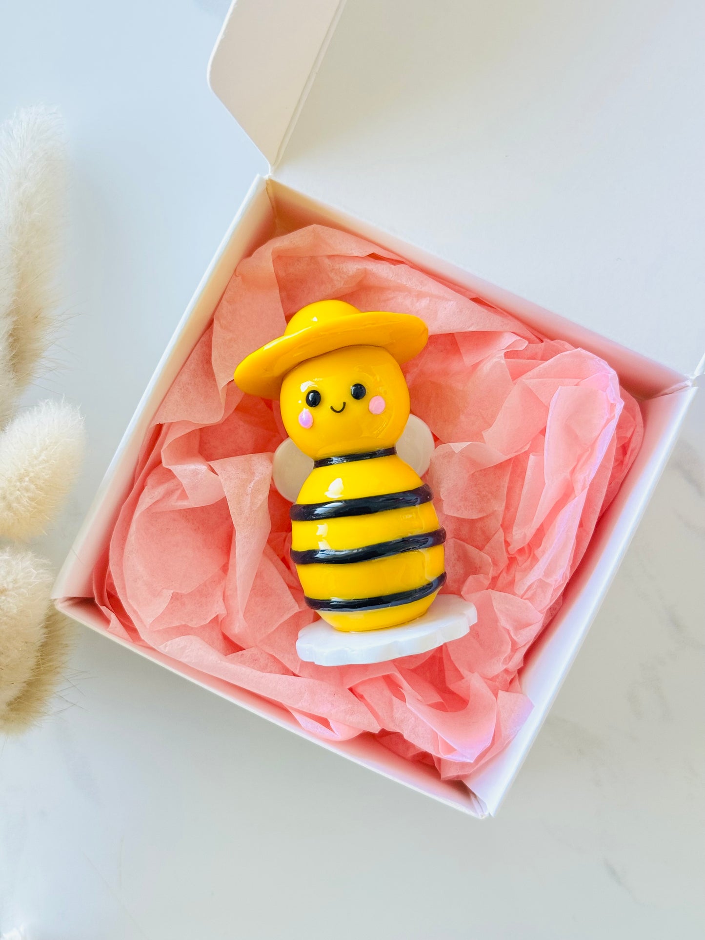 Toy bee figure in a gift box with pink tissue paper