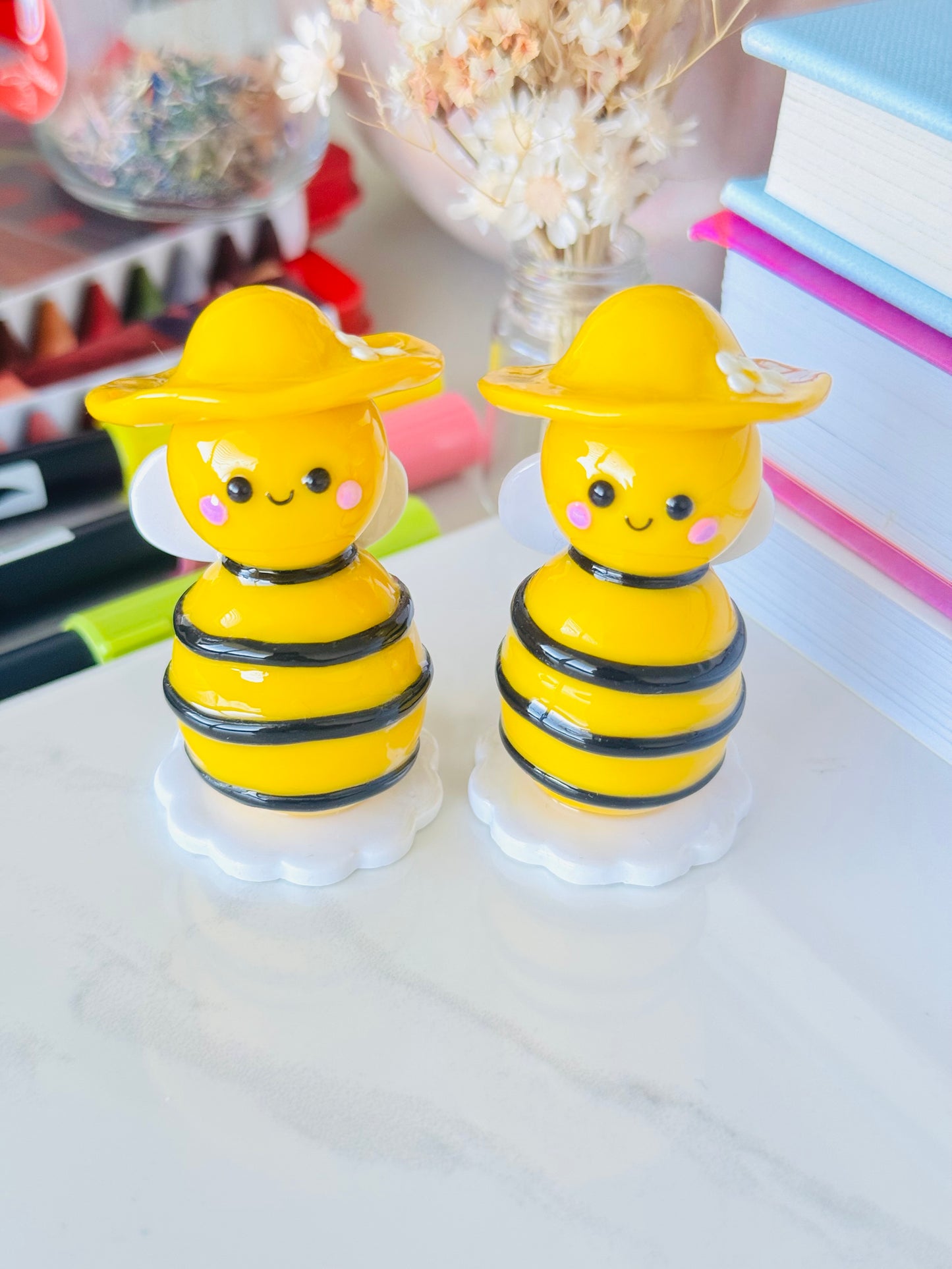 Two yellow bee-shaped objects on a white surface with a blurred background.